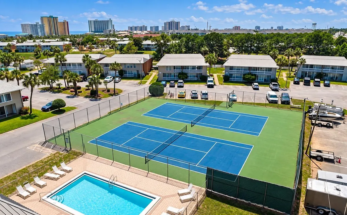 Aerial view of two tennis courts beside a community pool