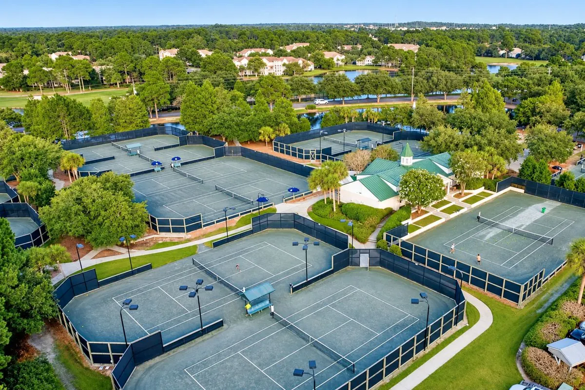 Aerial view of a large tennis center with a green-roofed clubhouse
