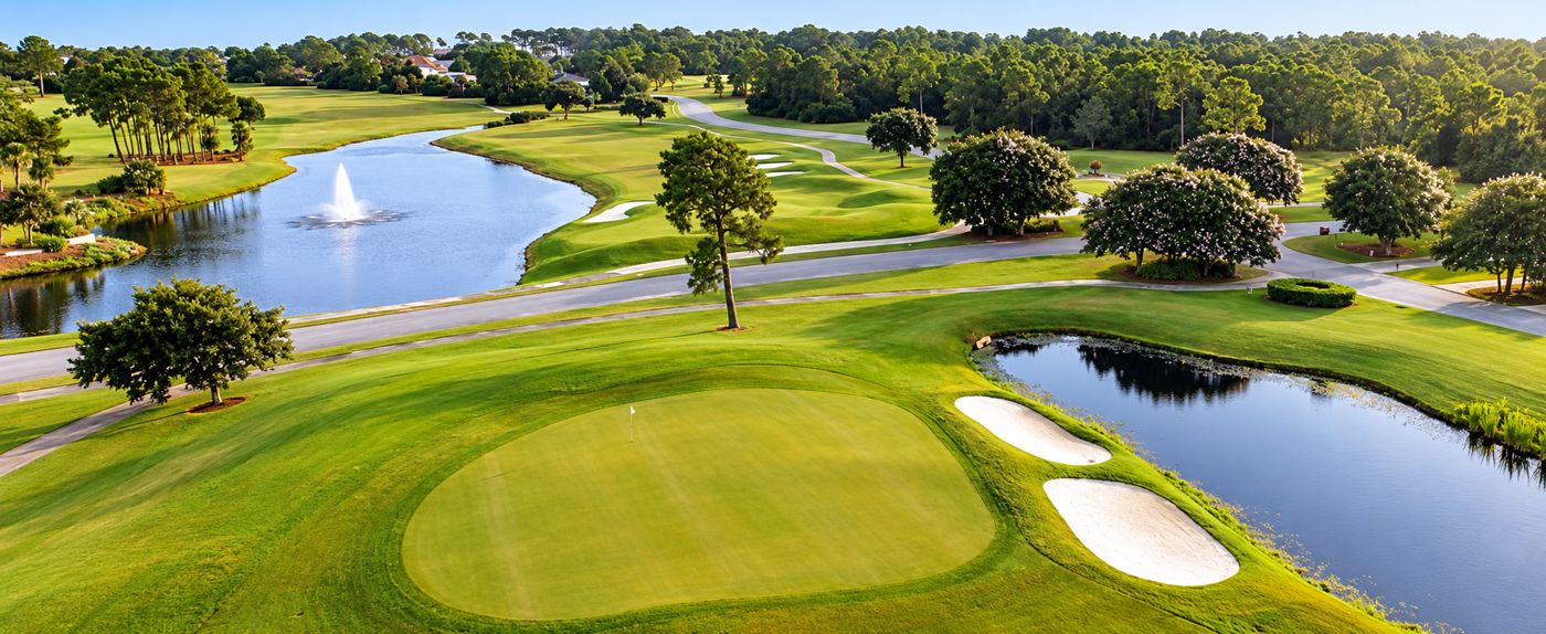 Aerial view of a green beside a pond, with a fountain lake beyond